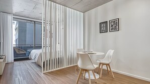 A modern room with a wooden floor, a bed, a balcony with a view, and two framed artworks on the wall. - Urban Rent - Departamentos en el corazon de Belgrano (Buenos Aires)