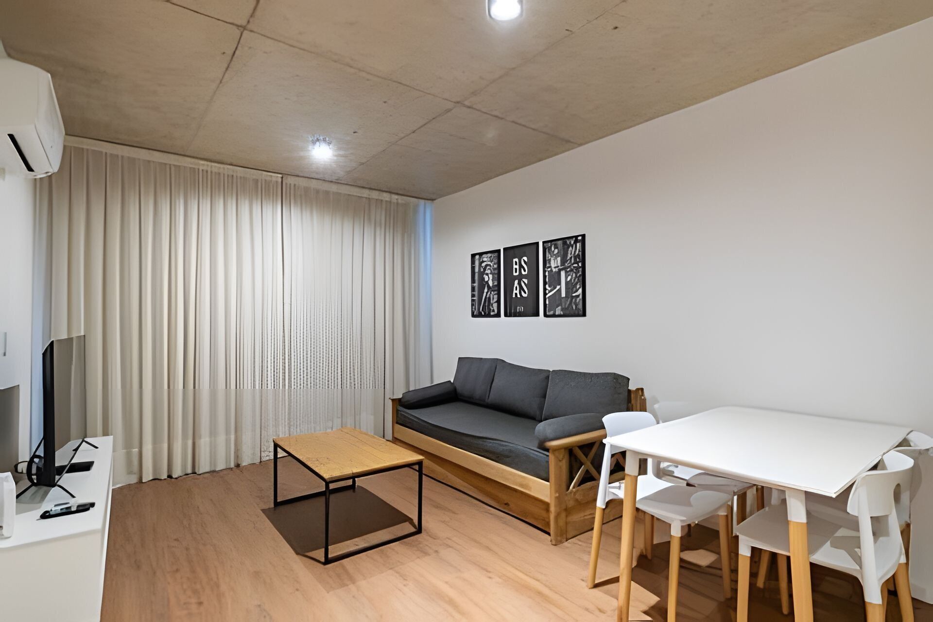 Una sala de estar moderna con un sofá, una mesita y un comedor con sillas.