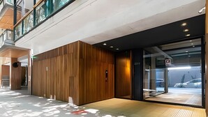 A modern building entrance with a wooden facade, a glass door, and a visible parking area outside. - Urban Rent - Departamentos en el corazon de Belgrano (Buenos Aires)