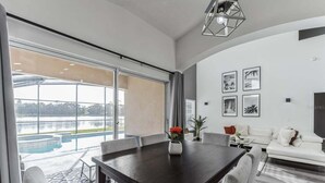 Ein modernes Wohnzimmer mit Essbereich, großen Fenstern und Blick auf einen Pool.