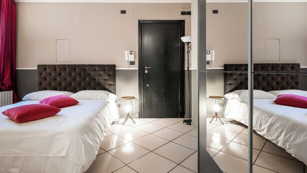 A hotel room with two beds, a black door, a mirror, and a bedside lamp. - Studio Fusari a Piazza Maggiore by Wonderful Italy (Bologna)