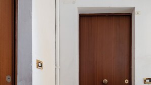 A wooden door with a doorknob, a welcome mat, and a light switch above it. - Studio Fusari a Piazza Maggiore by Wonderful Italy (Bologna)