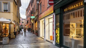 A cobblestone street lined with shops, including a restaurant and a pizzeria. - Studio Fusari a Piazza Maggiore by Wonderful Italy (Bologna)