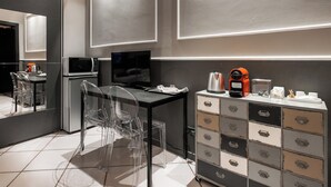 A modern hotel room with a desk, clear chairs, a television, a microwave, a coffee maker, and a storage cabinet. - Studio Fusari a Piazza Maggiore by Wonderful Italy (Bologna)
