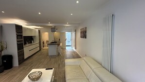 Eine moderne Küche mit integrierten Geräten, einer zentralen Kochinsel und einem Essbereich mit weißem Sofa.