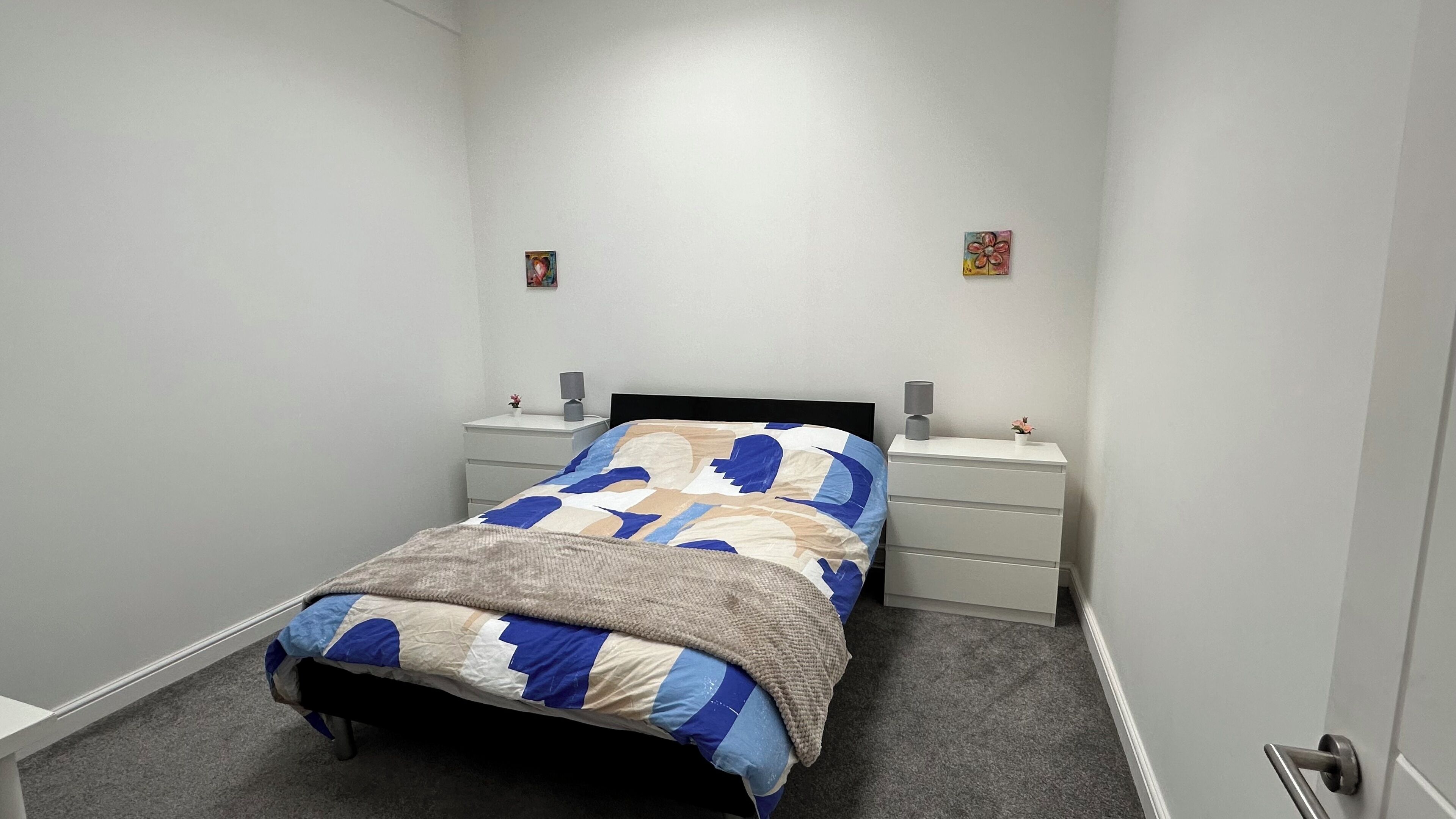 Une chambre à coucher avec un lit, des tables de chevet et une commode.
