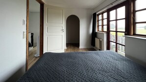 Ein Schlafzimmer mit Bett, Tür, Fenster und Heizkörper.