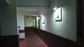 A narrow hallway with a red carpet, white walls, and framed pictures on the walls. - Gallery Boutique Hotel (Baku)