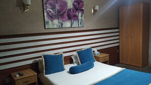 A hotel room with a bed, two bedside tables, a nightstand, a wardrobe, and a painting on the wall. - Gallery Boutique Hotel (Baku)