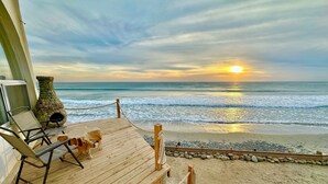 A wooden deck with a chair and a stone vase overlooking the beach at sunset. - SECLUDED One-of-a-Kind beachfront bungalow!  (Playas De Rosarito, B.C.)
