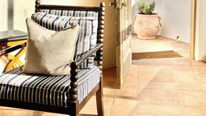 A room with a wooden chair, a framed artwork, and a view of the ocean through an open door. - SECLUDED One-of-a-Kind beachfront bungalow!  (Playas De Rosarito, B.C.)
