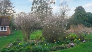 A garden with flowering plants, a small brick building, and trees. - 1 bedroom accommodation in East Tytherley (East Tytherley)
