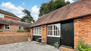 A brick cottage with a black door, white-framed windows, and a gravel driveway. - 1 bedroom accommodation in East Tytherley (East Tytherley)