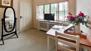 A room with a desk, chair, television, and a window with blinds. - 1 bedroom accommodation in East Tytherley (East Tytherley)