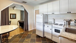Una cocina con armarios blancos, un refrigerador, un horno y un lavamanos.