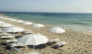 A beach with rows of white umbrellas and lounge chairs. - Il Ciclamino (Melendugno)