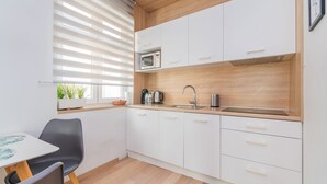 Una cocina compacta con gabinetes blancos, microondas, fregadero y cafetera.