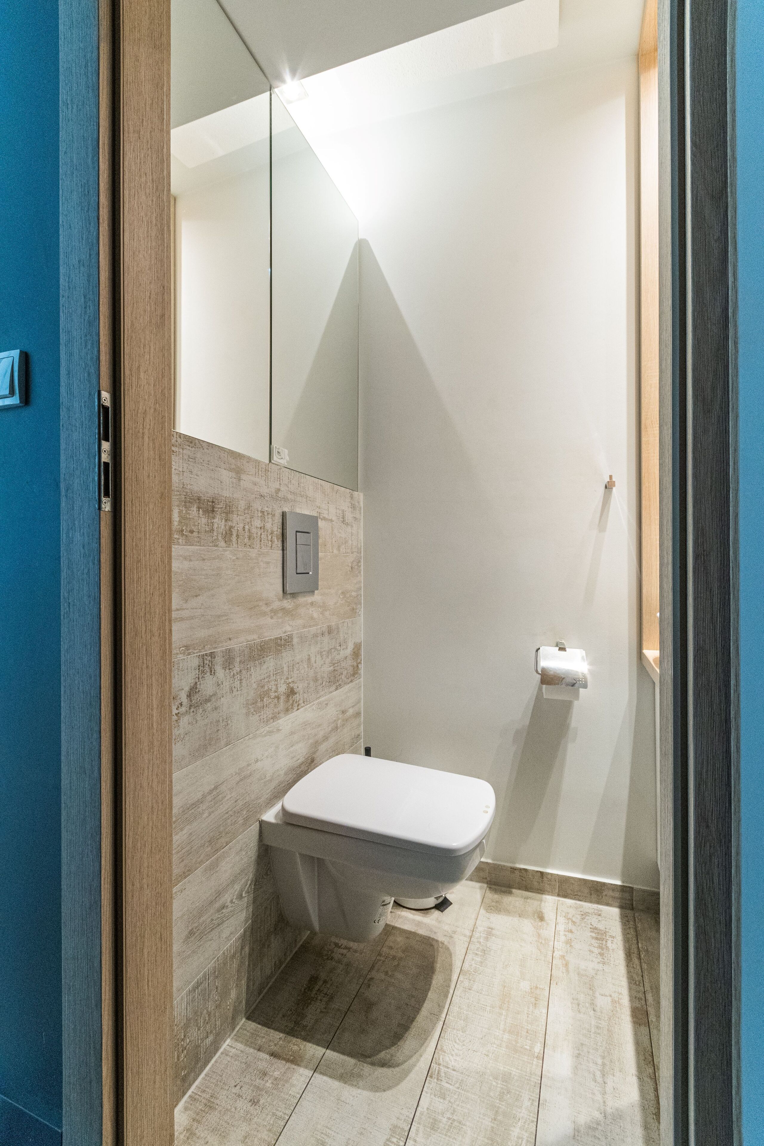 Un baño moderno con inodoro, dispensador de toallas y espejo.