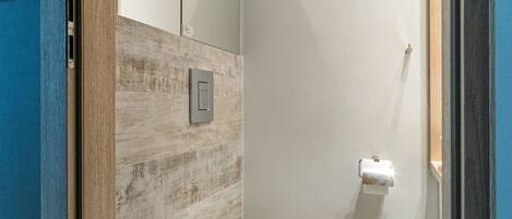 Un baño moderno con inodoro, dispensador de toallas y espejo.
