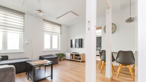 Una sala de estar moderna con un sofá, una mesa de centro y un televisor. Hay un comedor con sillas y una mesa.