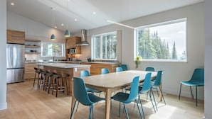 Une cuisine moderne dotée d’un îlot central, de tabourets de bar et d’une table à manger avec des chaises.