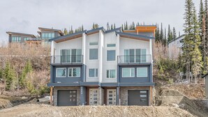 Un immeuble moderne à deux étages, doté d’un garage, de grandes fenêtres et d’un balcon.
