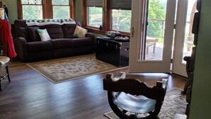 A living room with a dark brown sofa, a wooden coffee table, and a patterned rug. - Paradise. Front deck. All comforts of home.  Great view. Serenity. (Keuka Park)