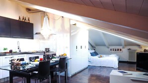 A modern kitchen with a dining area, a loft bedroom, and a living area with a TV. - Studio San Felice by Wonderful Italy (Bologna)