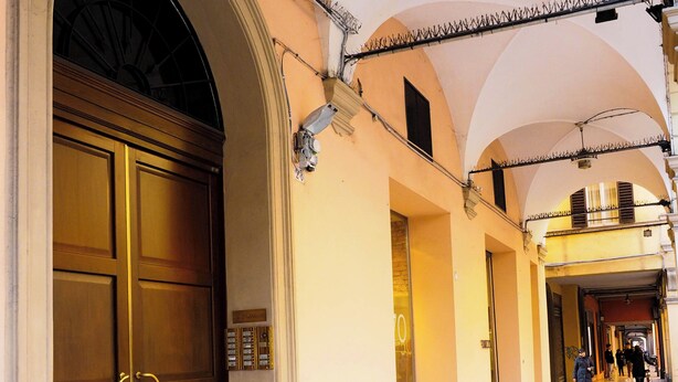 A corridor with arched ceilings, a large wooden door, and a tiled floor. - Studio San Felice by Wonderful Italy (Bologna)