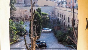 A courtyard with a gravel path, parked cars, and buildings in the background. - Studio San Felice by Wonderful Italy (Bologna)