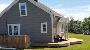 Een gelijkvloers huis met een veranda, een terras en een schoorsteen.