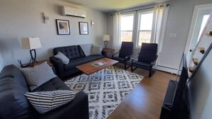 Een woonkamer met een bank, fauteuils, een salontafel en een kamerkleed met dessin.
