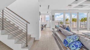 Ein modernes Wohnzimmer mit Treppe, Sofa und Blick ins Freie.