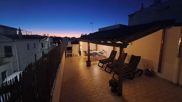 A rooftop patio with a pergola, outdoor seating, and a barbecue area.