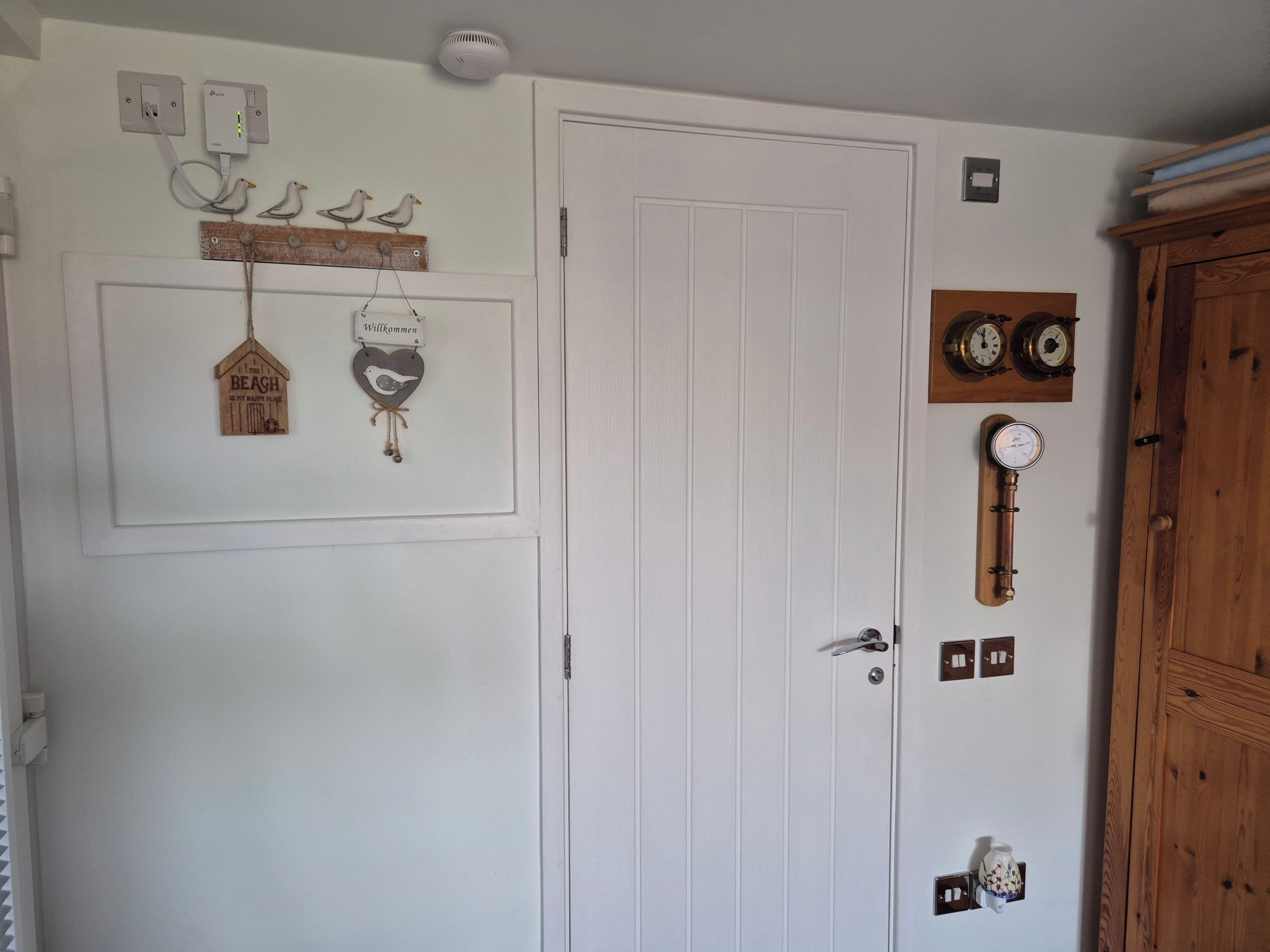 A white door with a bird decoration, a welcome sign, and a wall-mounted clock.