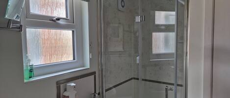 A bathroom with a window, a sink, a shower, and a toilet.