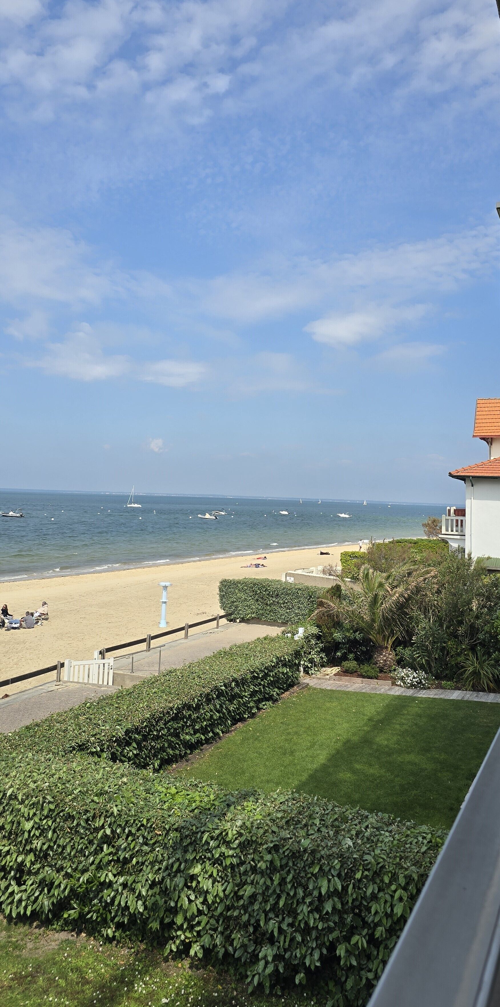 Vista costanera amb una platja sorrenca, alguns vaixells i un cel serè.