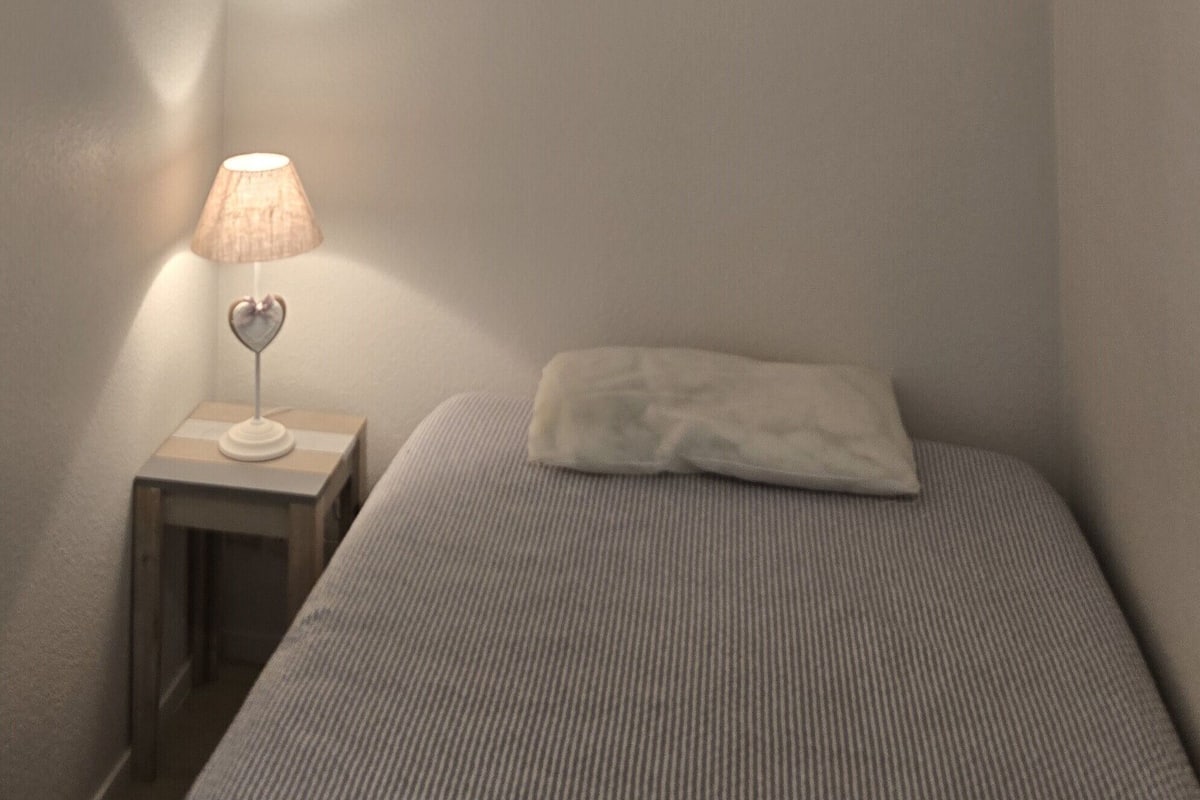 Un dormitorio con cama, mesita de noche con lámpara y lámpara colgante.