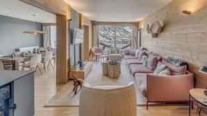 Una sala moderna con un conjunto de sofá, un comedor con mesa y sillas, y vistas a un paisaje nevado a través de amplios ventanales.