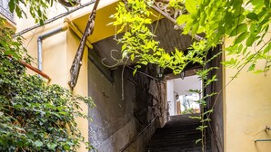 A stone staircase leading up to a building entrance, surrounded by greenery and a yellow wall. - Smooth Vibes at Chiaia by Napoliapartments (Naples)
