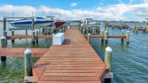 Une jetée en bois qui mène à une marina où sont amarrés des bateaux.