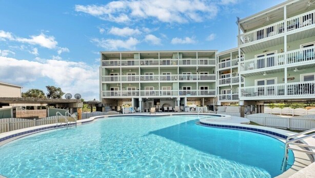 Une piscine entourée d’un immeuble à plusieurs étages doté de balcons.