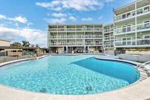 A swimming pool surrounded by a multi-story building with balconies.