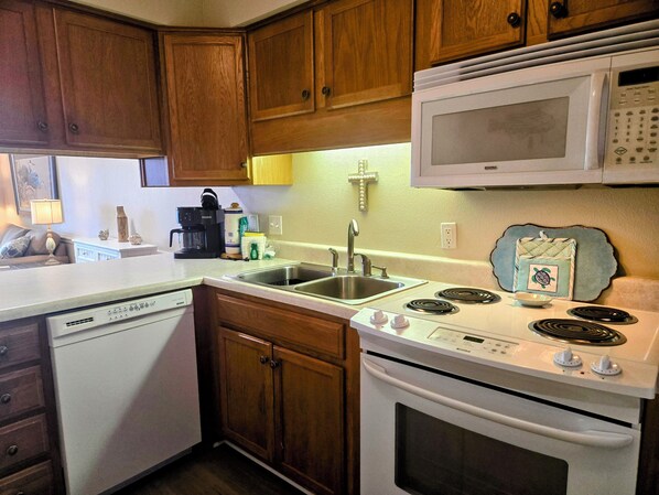 A kitchen with wooden cabinets, a microwave, a stove, a dishwasher, and a sink.