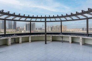 A rooftop terrace with a pergola, a sink, and a view of a cityscape. - Jewelz Residences Studio in Dubai (Dubai)