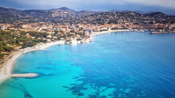An aerial view of a coastal town with a curved bay, buildings, and a mountainous backdrop. - Apartment with garden in Sainte-Maxime (Sainte-Maxime)