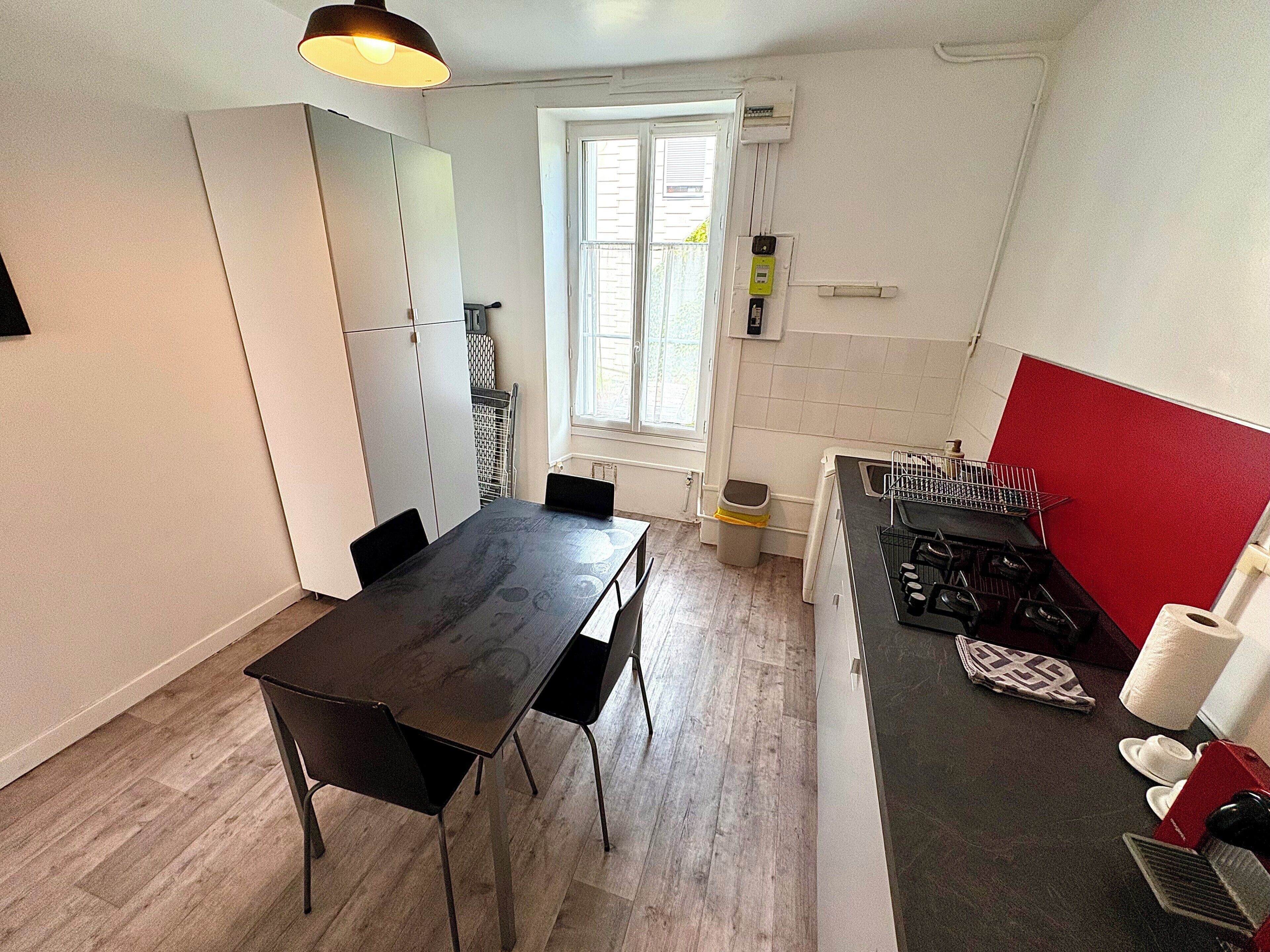Une cuisine de taille réduite comprenant une table à manger, des chaises, une cuisinière et une fenêtre.