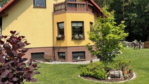 Une maison jaune avec un toit rouge, un balcon doté de balustrades en bois et une antenne parabolique.