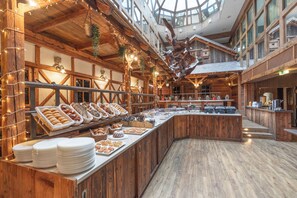 Een buffet met diverse gerechten, houten inrichting en een hoge plafond met natuurlijk licht.