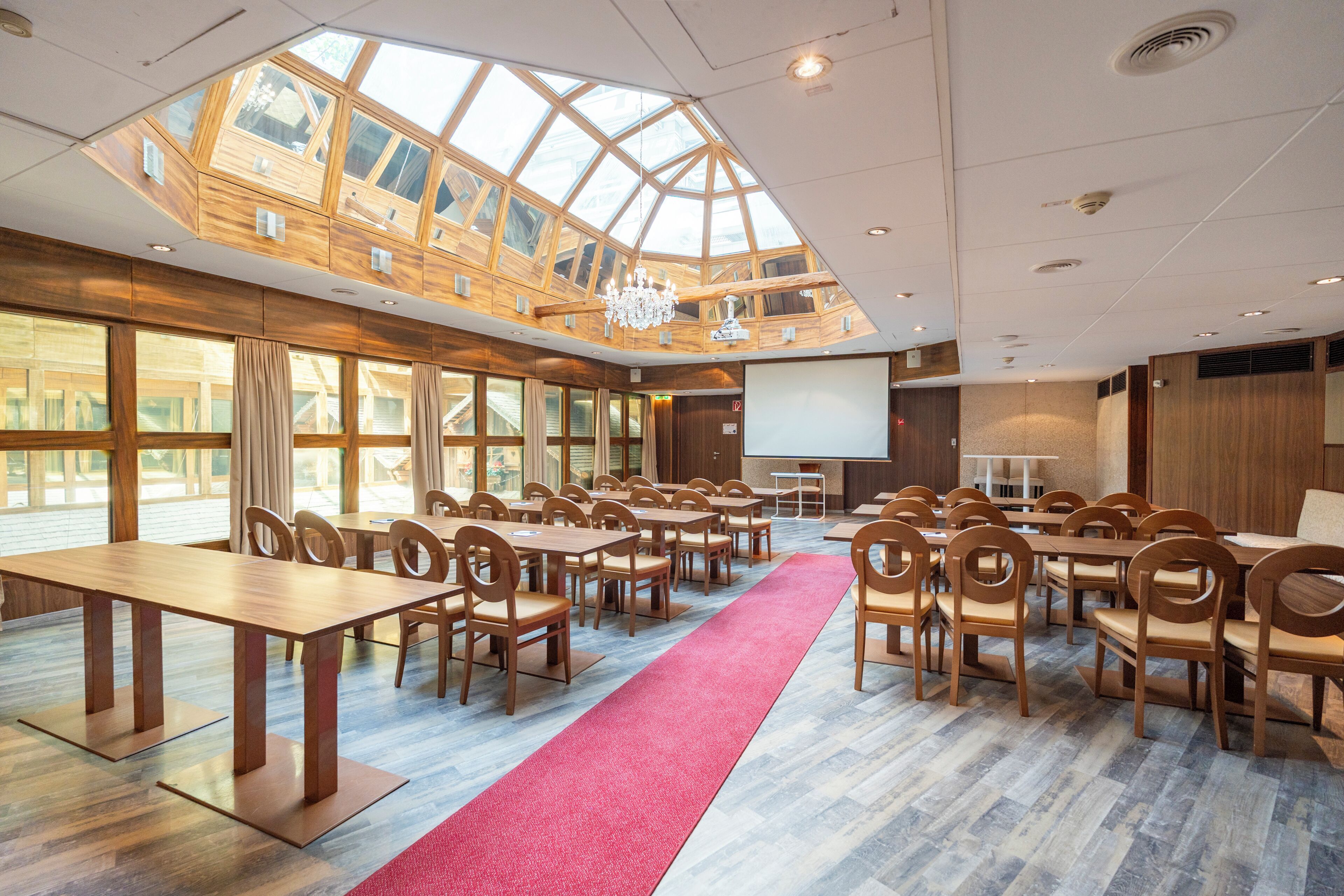 A conference room with a high ceiling, large windows, and a red carpet.